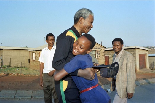 El-entonces-líder-contra-el-apartheid-o-segregación-Nelson-Mandela-abraza-a-una-niña-en-el-pueblo-de-Soweto-en-octubre-de-1990-ALEXANDER-JOE-AFP-GETTY-523x348